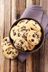Chocolate chip cookies in bowl on brown wooden background