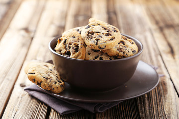 Chocolate chip cookies in bowl on brown wooden background