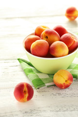 Fototapeta na wymiar Fresh apricots in bowl on a white wooden background