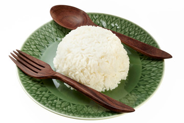 Rice on green plate with wood spoon and fork isolated on white background