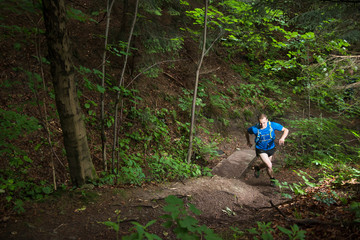single man running up the hill on the trail in the woods