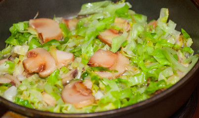 Cooking cabbage with mushrooms in fried pan