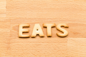 Word eats biscuit over the wooden background