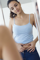 Fototapeta premium Beautiful young woman measuring fat level on her abdominal.