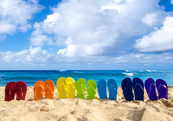Obraz premium Colorful flip flops on the sandy beach