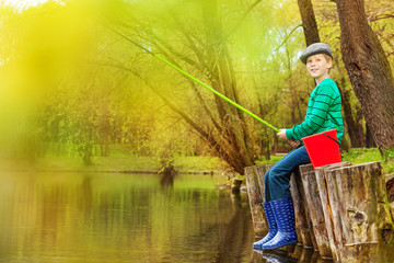 Boy fishing near beautiful pond with fishrod