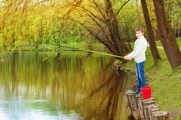 Fototapeta na wymiar Boy standing and fishing near the pond