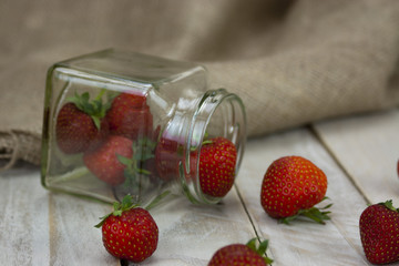 Stawberries in a jar and spilt on table