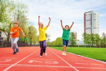 Kids in colorful uniforms with arms up running