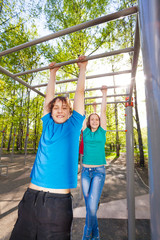 Boy and girl hanging on the brachiating bar