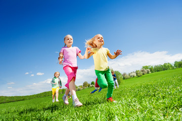 Happy girls and other kids running in green field