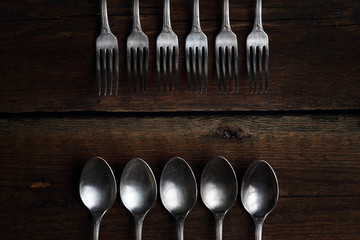 Silver forks and spoons on wooden background.