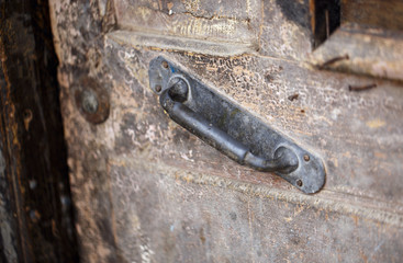 Detail of a rusty metal handle on old wooden door.