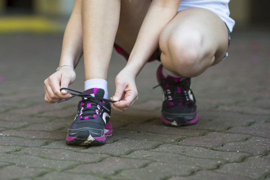 Young woman is tying the laces before running. Close-up, running, healthy lifestyle.