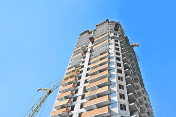 Crane and building construction site against blue sky