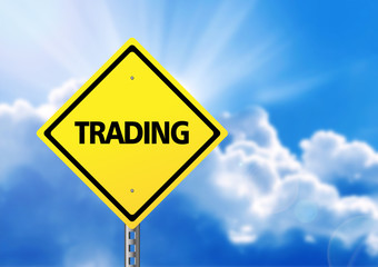 Yellow road sign with text trading.