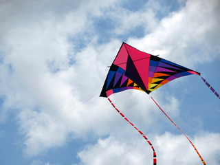 A brightly colored kite soars up to the clouds.