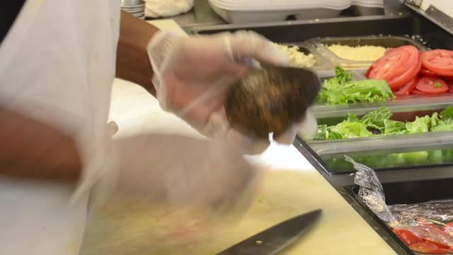 A chef in a restaurant kitchen slicing an avocado
