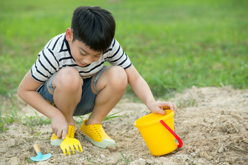 Asian boy playing with toys in garden