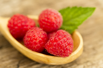 ripe raspberry in a spoon with mint leaves closeup on wooden background