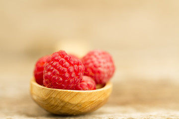 ripe raspberry in a spoon closeup on wooden background