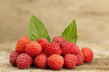 ripe raspberries with mint leaves closeup on wooden background, top view