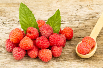 ripe raspberries with mint leaves closeup on wooden background, top view