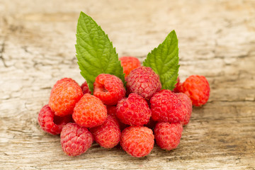 ripe raspberries with mint leaves closeup on wooden background, top view