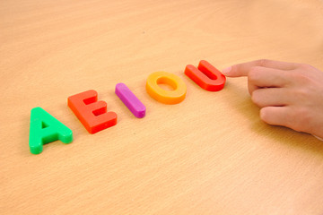 Letters a e i o and u with child hand, school concept