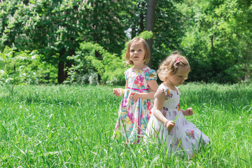 Adorable little girls (sisters) in the summer garden.