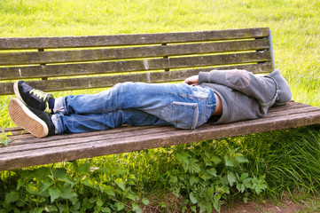 Teenager liegt auf einer Parkbank im Freien