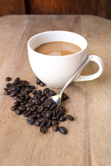 Coffee cup and beans on a wood background