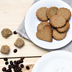 Ginger biscuits, cinnamon, a cup of hot coffee. Walnuts, hazelnuts on a wooden background