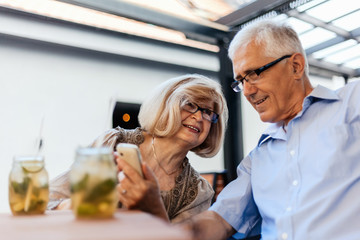 Mature Couple In Cafe Using Technology
