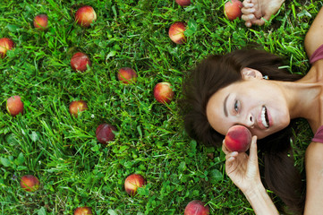 Happy Portrait of beautiful girl on the grass surrounded by peaches