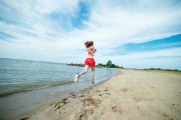 Young lady running at the sunny summer sand beach. Workout.  Jog