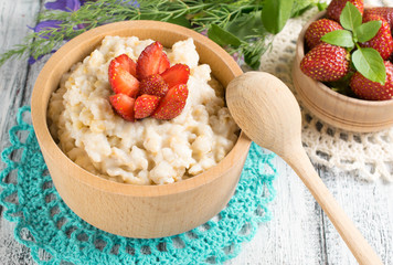 Oatmeal with strawberries in the wooden bowl