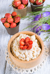 Oatmeal with strawberries in the wooden bowl