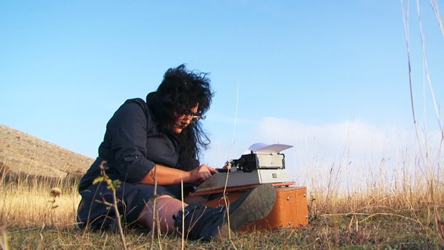 Funny Woman Typing On Vintage Typewriter Sitting On The Ground