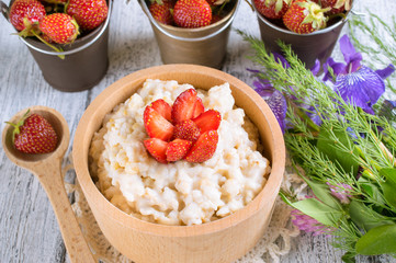 Oatmeal with strawberries in the wooden bowl