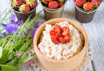 Oatmeal with strawberries in the wooden bowl