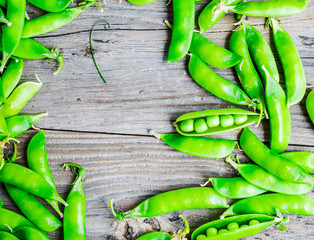 green peas in pods young on gray wooden background, rustic,