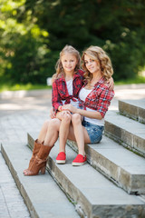 Portrait of a beautiful mother and daughter in the summer park  