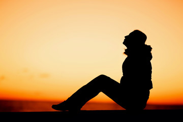 Silhouette of a woman sitting on the edge over beautiful red