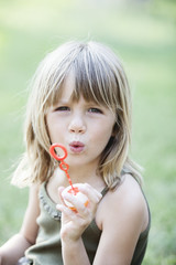 little girl with soap bubbles having fun outdoors. Looking at the camera