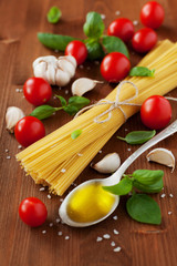 Uncooked spaghetti, cherry tomato, basil, garlic and olive oil, ingredients for cooking pasta, selective focus
