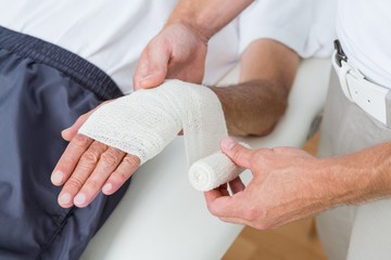 Doctor bandaging his patient hand