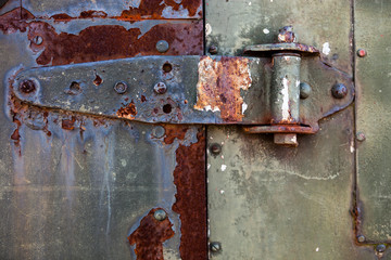 Old rusty metal hinge on the metal door