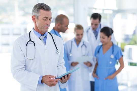 Doctor looking at clipboard while his colleague discussing 
