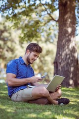 Fototapeta premium Hipster using laptop and phone in the park